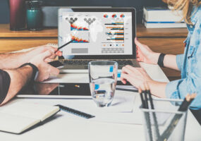 Businessman and businesswoman sitting at table in front of laptop and working.Graphs,charts and diagrams on PC screen. martech tools