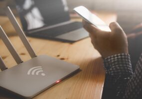 closeup of a wireless router and a person using smartphone on living room at home office