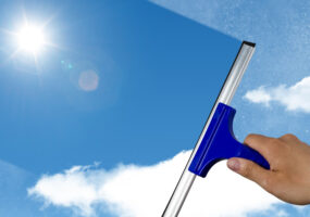 SaaS Apps, SaaS stacks, squeegee cleaning a dirty window, spring cleaning concept, blue sky