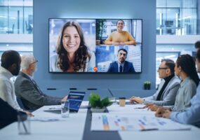 Video Conference Call in Office Boardroom Meeting Room: Executive Directors Talk with Group of Multi-Ethnic Entrepreneurs, Managers, Investors. Businesspeople Discuss e-Commerce Investment Strategy