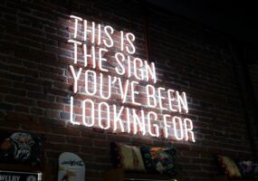 Neon lights saying "This is the sign you're looking for." digital signage content