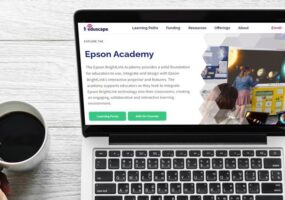 Mockup of Epson BrightLink Academy on a laptop. A person's hand holding a cup of coffee appears next to the laptop.