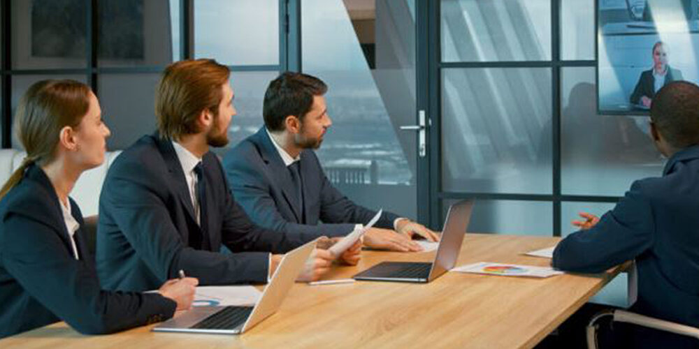 people sitting around conference table conducting hybrid meeting, using Kramer and Jabra conferencing solution