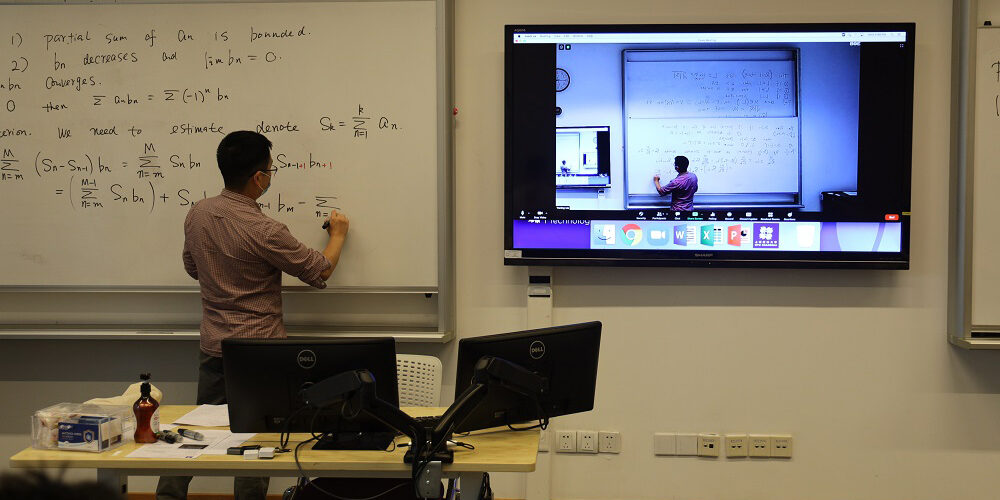 Shanghai NYU professor writing on whiteboard while Dante audio network distributes audio and video to remote learners