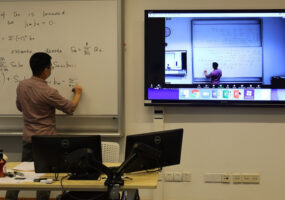 Shanghai NYU professor writing on whiteboard while Dante audio network distributes audio and video to remote learners